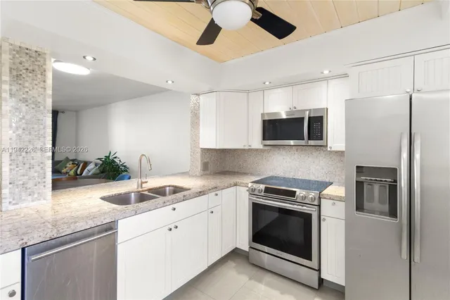 a kitchen with granite countertop a sink stainless steel appliances and white cabinets