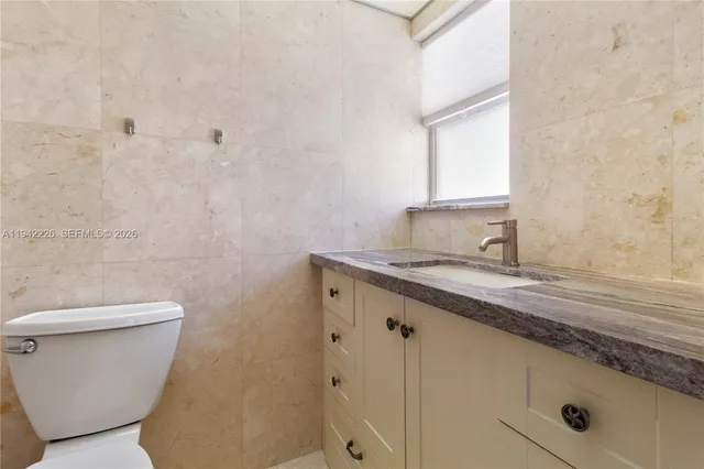 a bathroom with a granite countertop sink a toilet and a mirror