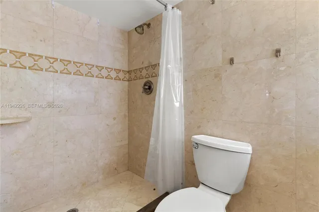 a white toilet sitting next to a shower