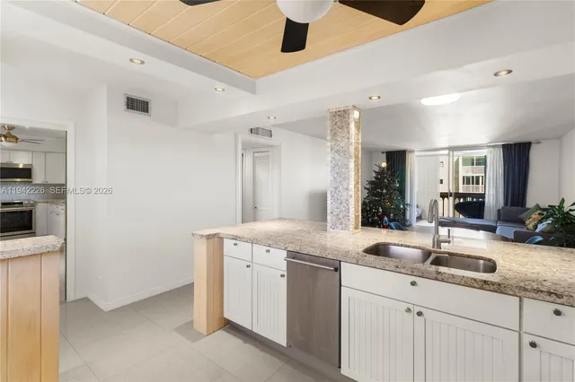 a kitchen with granite countertop a sink and white cabinets