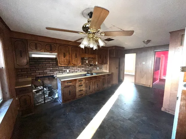 a kitchen with stainless steel appliances kitchen island granite countertop a stove a refrigerator a sink a dining table and chairs with wooden floor