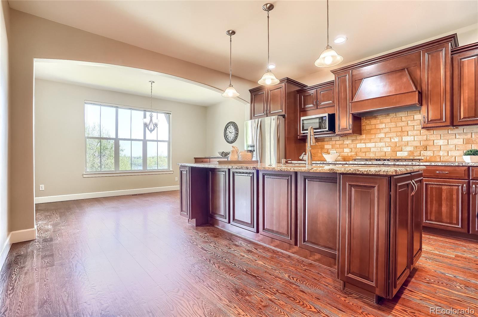 2363 Primo Road, Unit E Highlands Ranch, CO 80129 - Photo 8 of 36 a open kitchen with granite countertop a stove a sink and a wooden floors