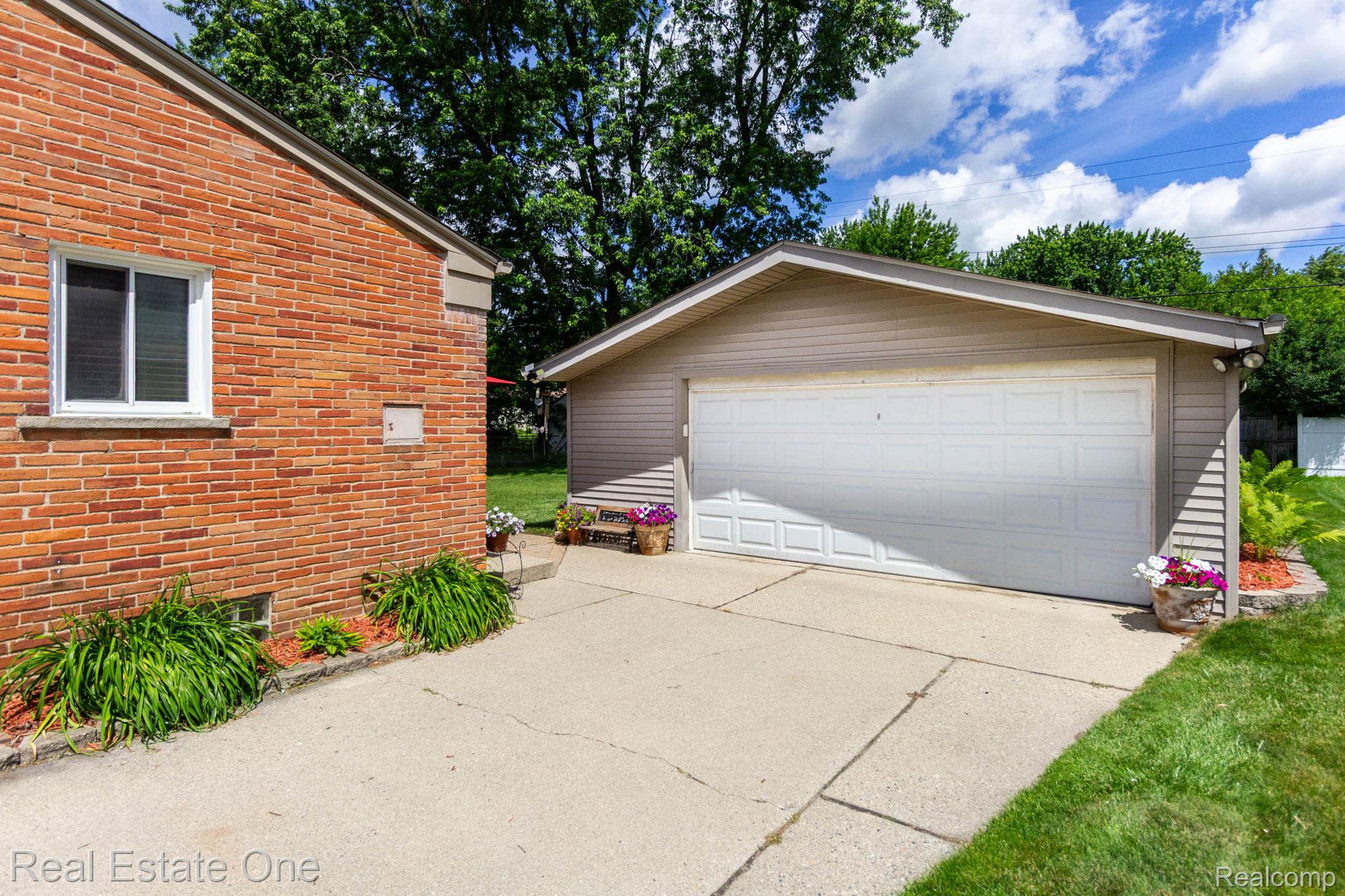 220 Winry Drive Rochester, MI 48307 - Photo 25 of 35 Detached garage with a paneled door, accompanied by a concrete driveway and brick exterior