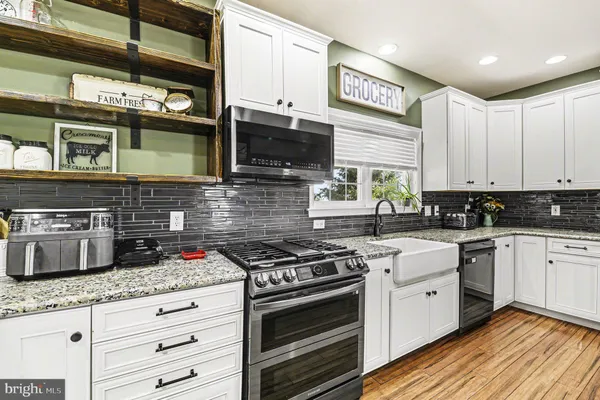 a kitchen with stainless steel appliances granite countertop a stove a sink and a microwave