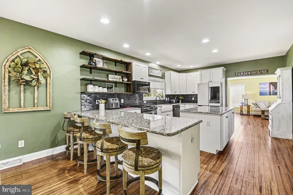 a kitchen with stainless steel appliances granite countertop a stove top oven a sink dishwasher and cabinets with wooden floor