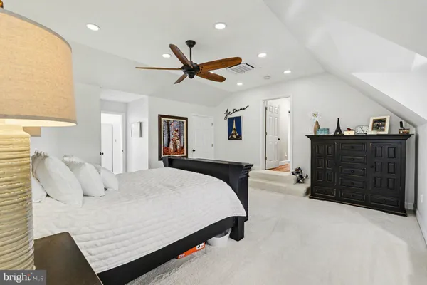 a spacious bedroom with a bed a dresser and a chandelier