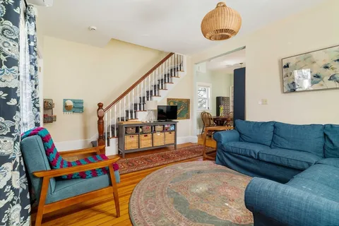 a living room with furniture stairs and a potted plant