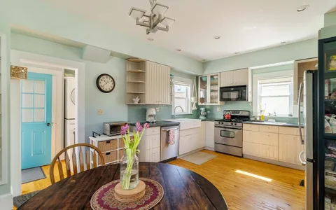 a kitchen with stainless steel appliances granite countertop a stove a sink dishwasher a dining table and chair with wooden floor