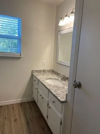 an empty room with wooden floor vanity and windows