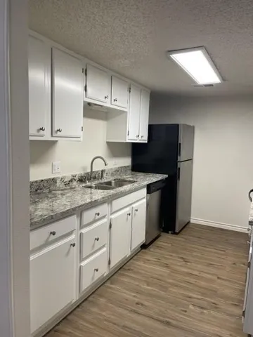 a kitchen with granite countertop a sink stainless steel appliances and cabinets