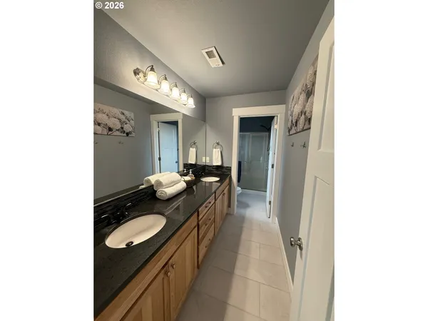 a spacious bathroom with a granite countertop sink a mirror and a shower
