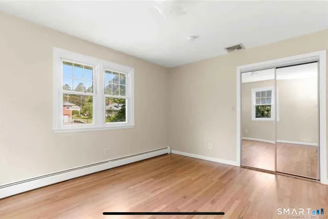 an empty room with wooden floor cabinet and windows