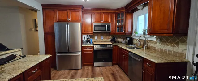 a kitchen with granite countertop stainless steel appliances a sink stove and refrigerator