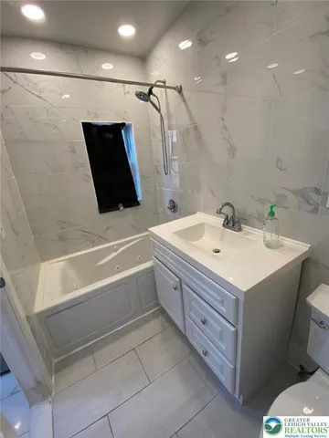 a bathroom with a granite countertop sink a toilet and shower