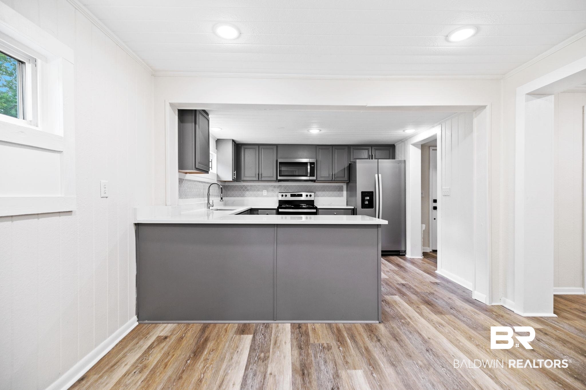 507 Byrne Street Bay Minette, AL 36507 - Photo 15 of 40 Kitchen with gray cabinets, stainless steel appliances, light wood-type flooring, and kitchen peninsula