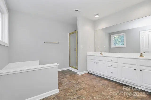 a spacious bathroom with double vanity sink a mirror and a toilet