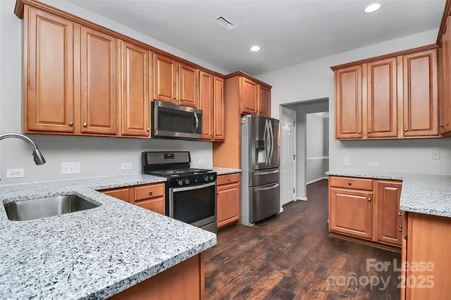 a kitchen with stainless steel appliances granite countertop a refrigerator stove top oven and sink