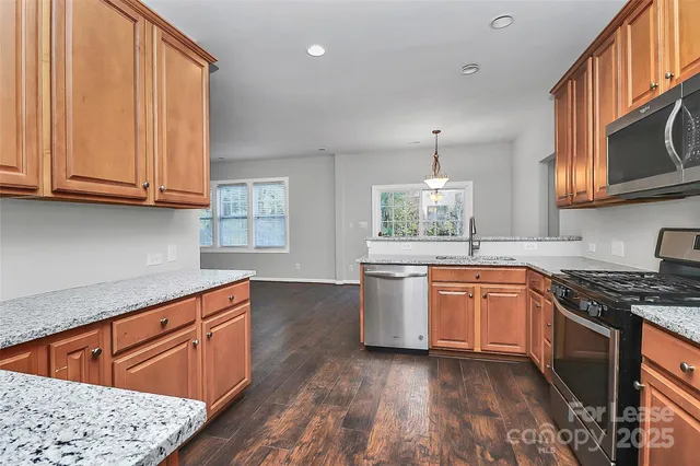 a kitchen with stainless steel appliances granite countertop wooden cabinets a sink and a stove