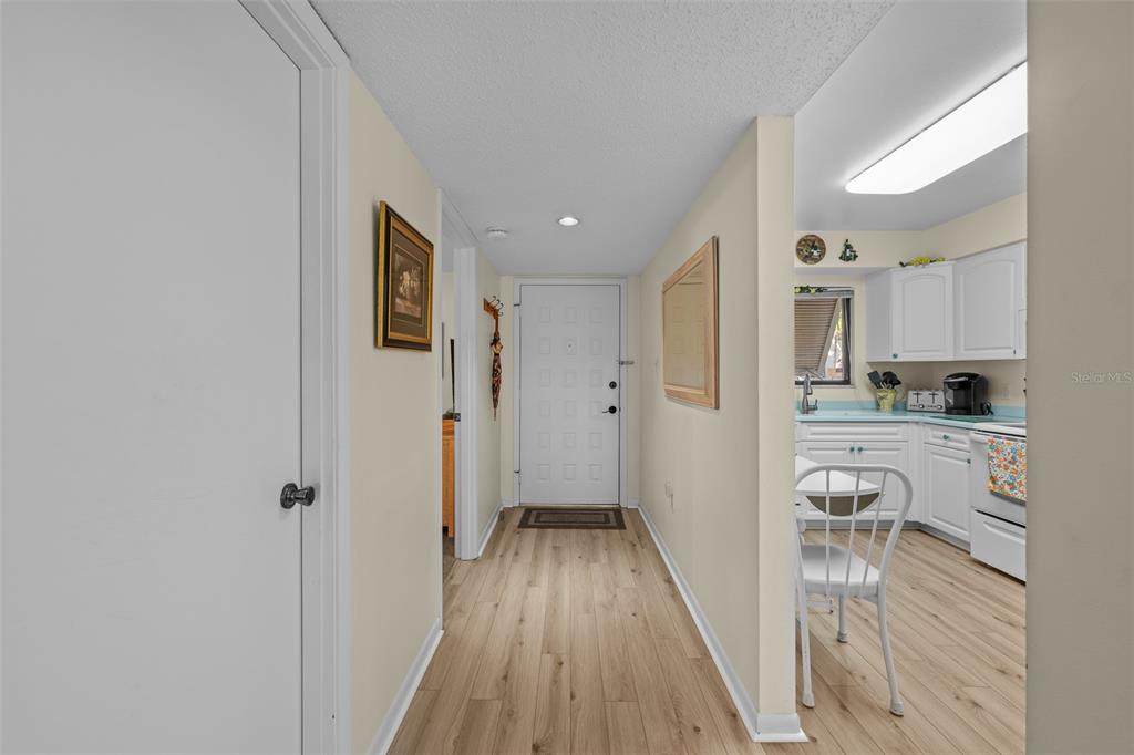 5290 Willow Links, Unit 57 Sarasota, FL 34235 - Photo 21 of 46 a view of a hallway with wooden floor and a kitchen