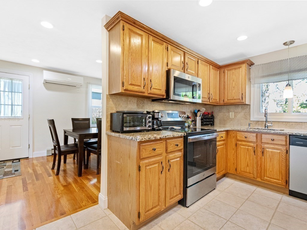 17 Central Street, Unit 2 Waltham, MA 02453 - Photo 4 of 39 a kitchen with stainless steel appliances granite countertop a stove top oven a sink dishwasher a dining table and chairs with wooden floor