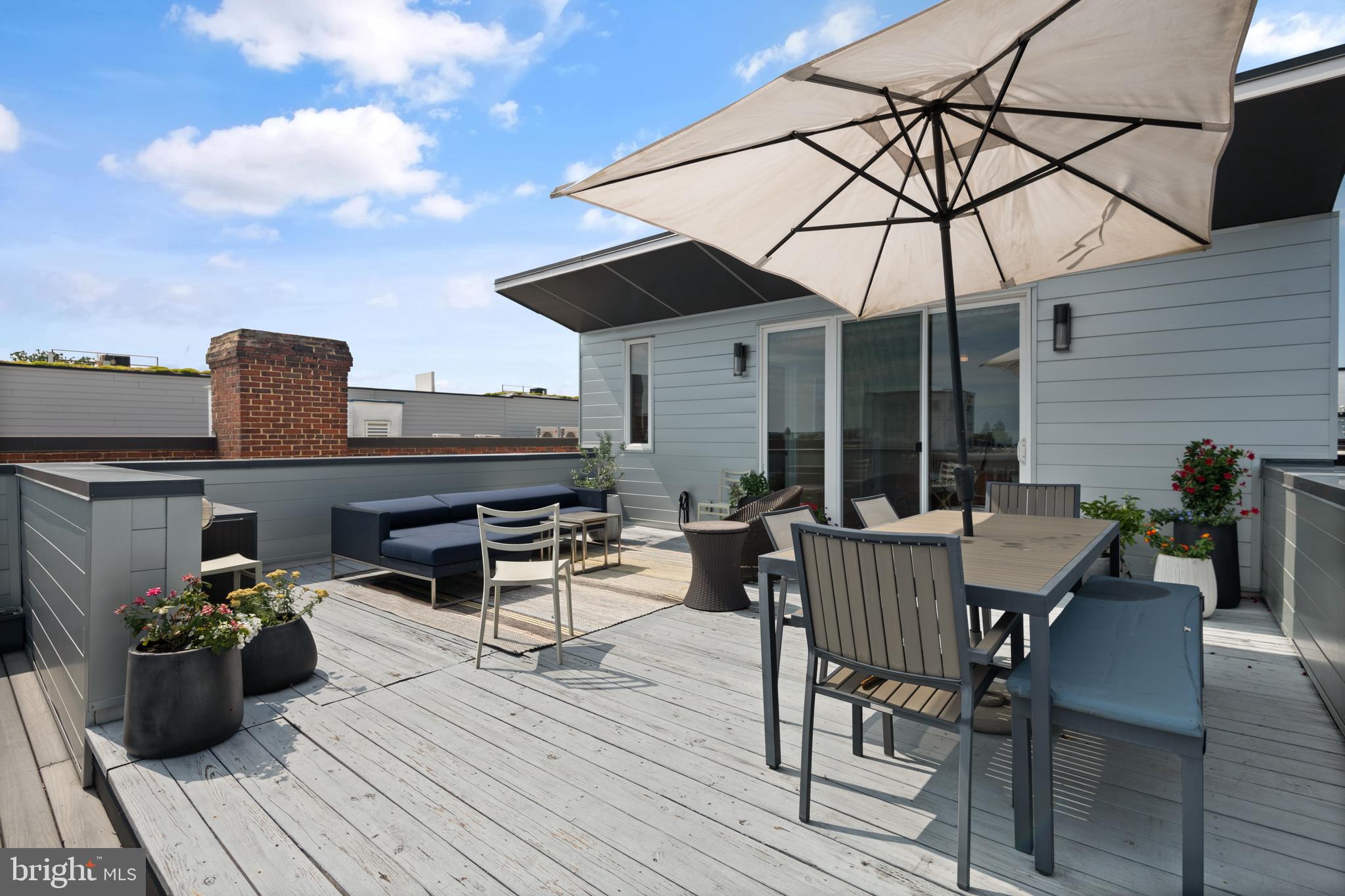 1436 Chapin Street Northwest, Unit F Washington, DC 20009 - Photo 38 of 41 a view of a roof deck with table and chairs under an umbrella