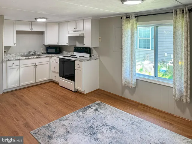 a kitchen with stainless steel appliances granite countertop a stove a sink and white cabinets
