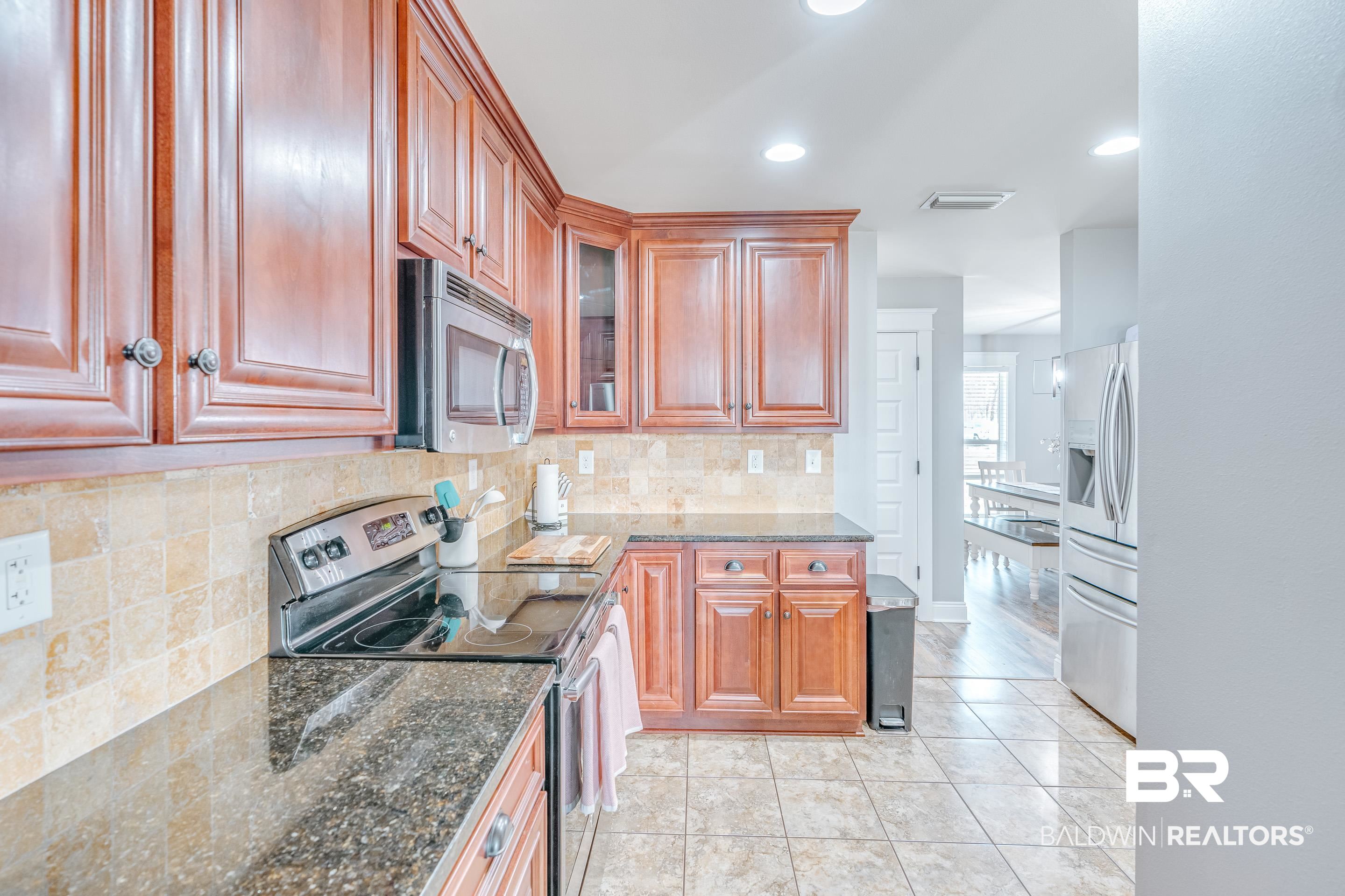 13235 Tom Gaston Road Mobile, AL 36695 - Photo 10 of 43 Kitchen with tasteful backsplash, light tile patterned floors, stainless steel appliances, and dark stone counters