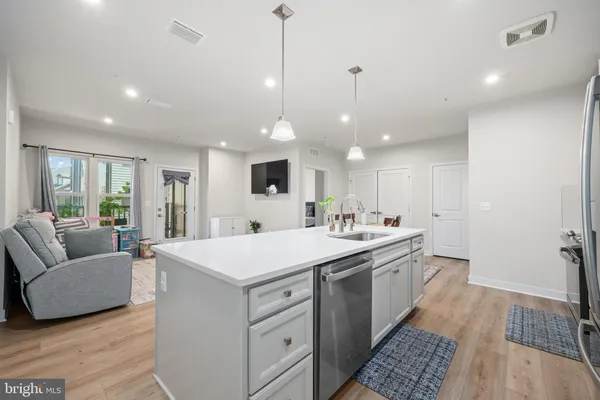 a large room with kitchen island a sink dishwasher a dining table and chairs with wooden floor