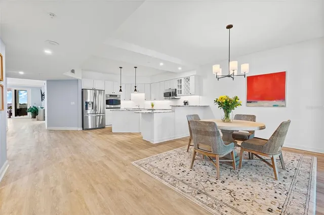 a view of a dining room and livingroom with furniture wooden floor a rug a chandelier