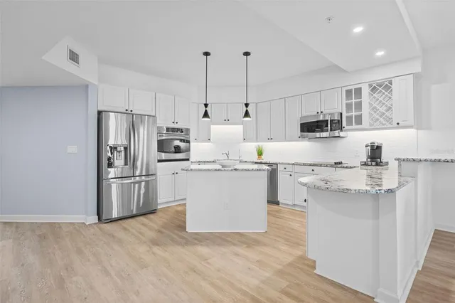 a kitchen with kitchen island white cabinets and stainless steel appliances