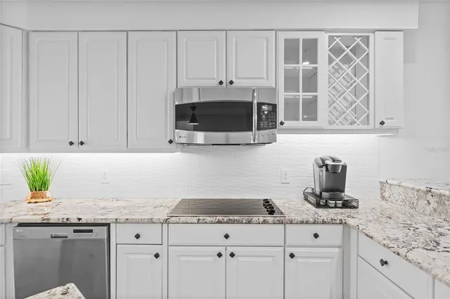 a kitchen with granite countertop white cabinets and a stove