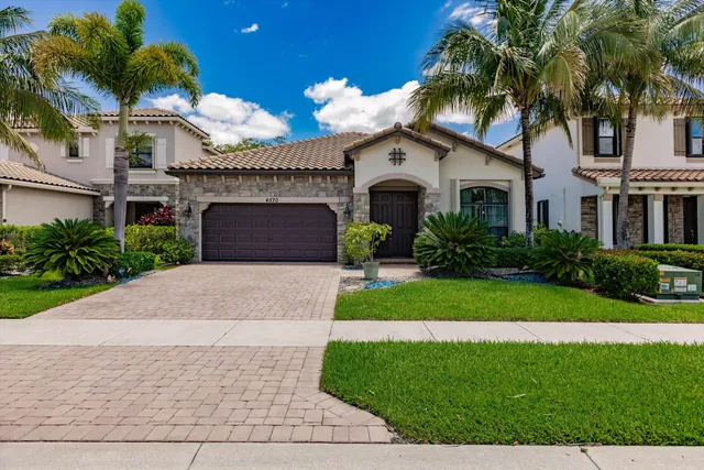 a front view of a house with a garden and palm trees