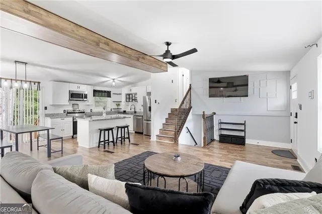 a living room with furniture kitchen view and a flat screen tv