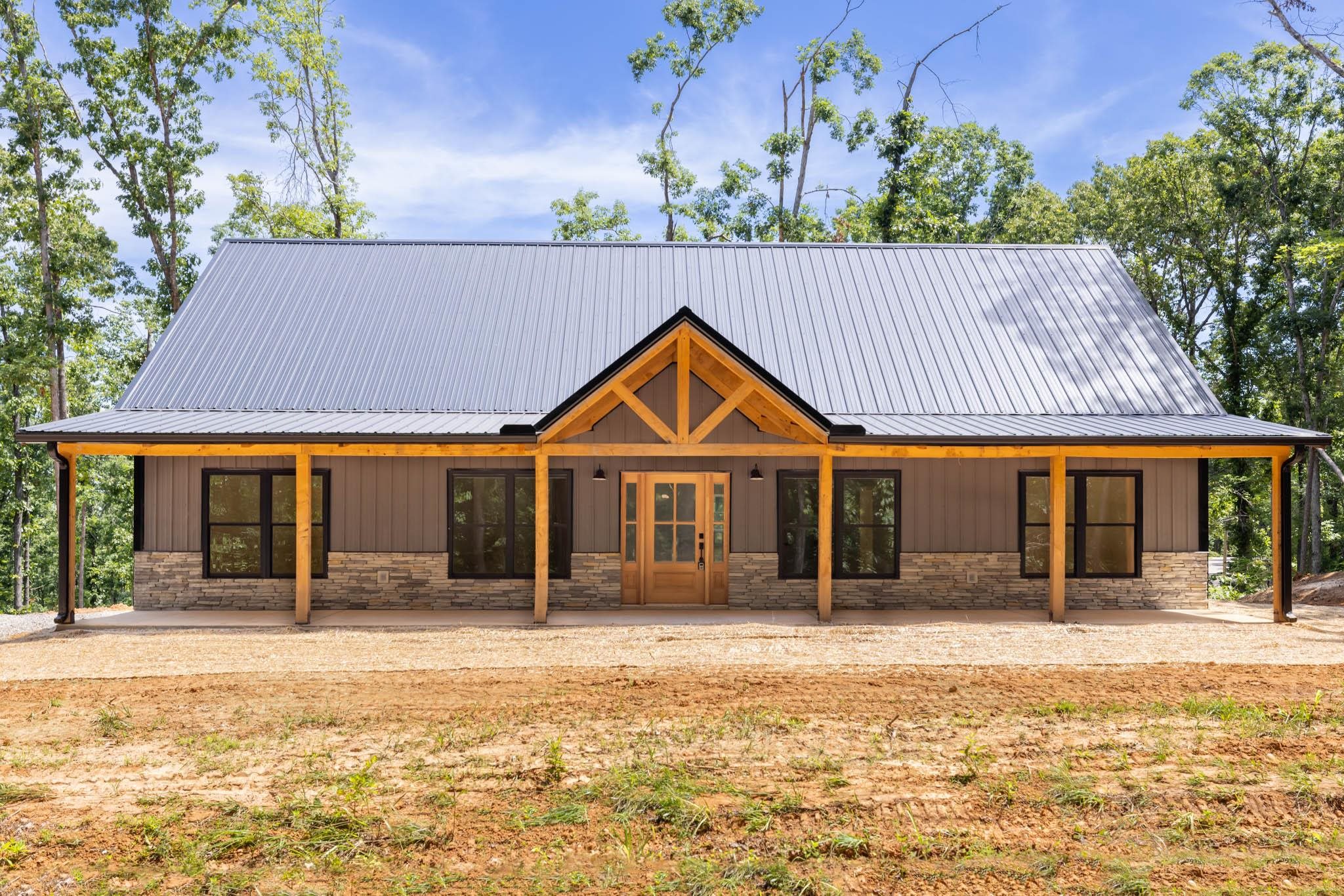 37 William Teague Lane Ramer, TN 38367 - Photo 1 of 39 Modern farmhouse exterior featuring a gray metal roof, wood-look siding, and natural stone accents