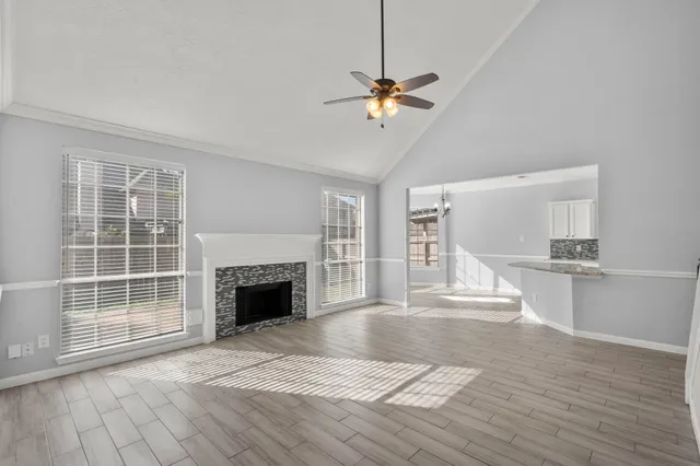 a view of an empty room with wooden floor fireplace and a window
