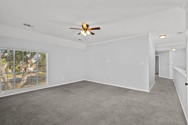 an empty room with windows and chandelier fan