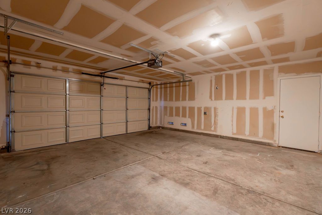 8379 Rockefeller Street Las Vegas, NV 89123 - Photo 16 of 36 An unfinished garage features a concrete floor and a sectional overhead door.