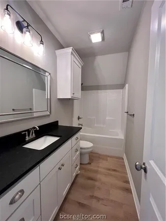 a bathroom with a granite countertop sink toilet a mirror and shower