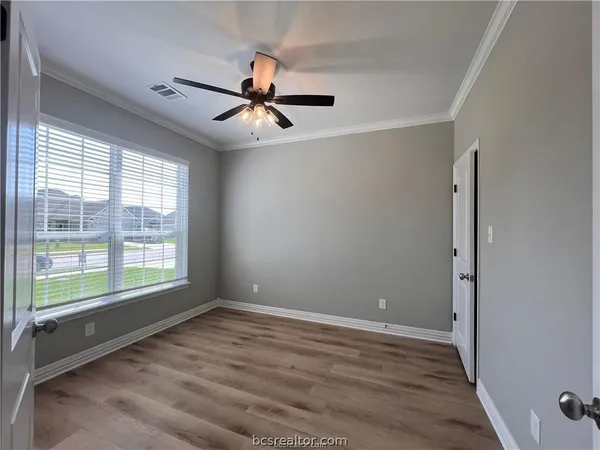 a view of an empty room with a window and wooden floor
