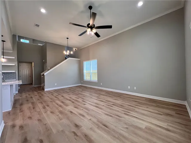 an empty room with wooden floor ceiling fan and window