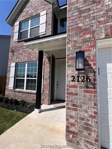 front view of a brick house with a yard