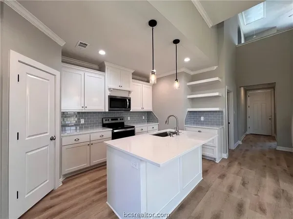 a kitchen with a sink a stove a refrigerator and white cabinets