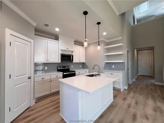 a kitchen with a sink a stove a refrigerator and white cabinets