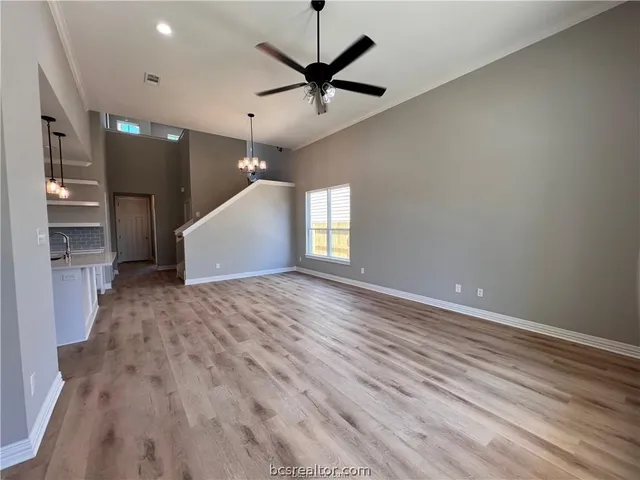 an empty room with wooden floor and a ceiling fan