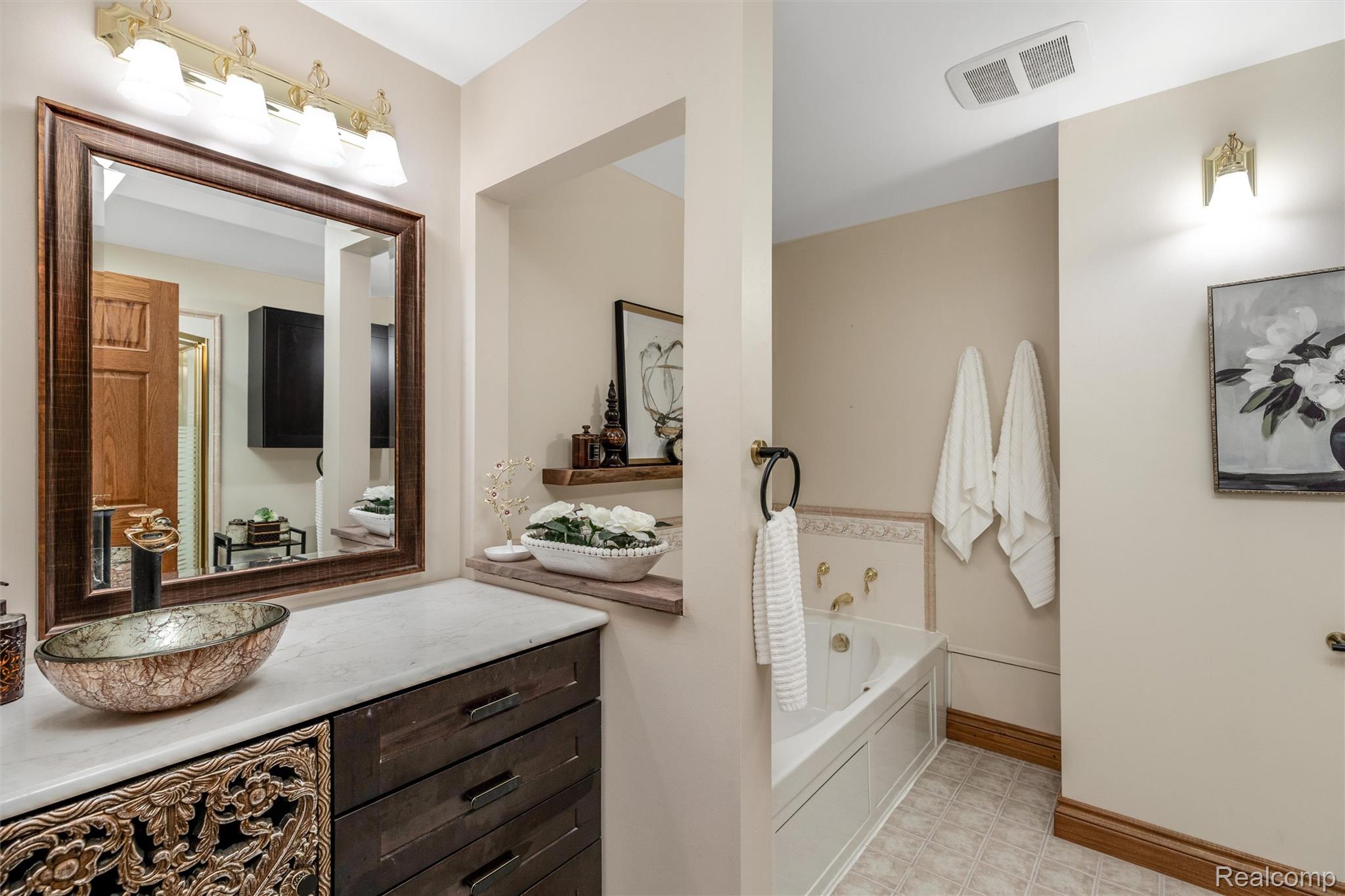 21280 Merriman Road New Boston, MI 48164 - Photo 41 of 65 Vessel sink set into a light-toned countertop, framed by a dark wood cabinet with decorative carving and drawer storage
