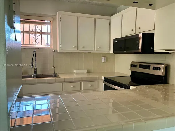 a kitchen with granite countertop white cabinets stainless steel appliances and sink