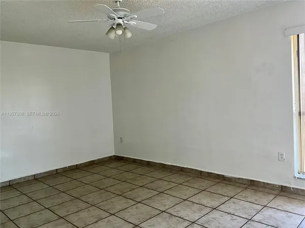 an empty room with a chandelier fan and windows