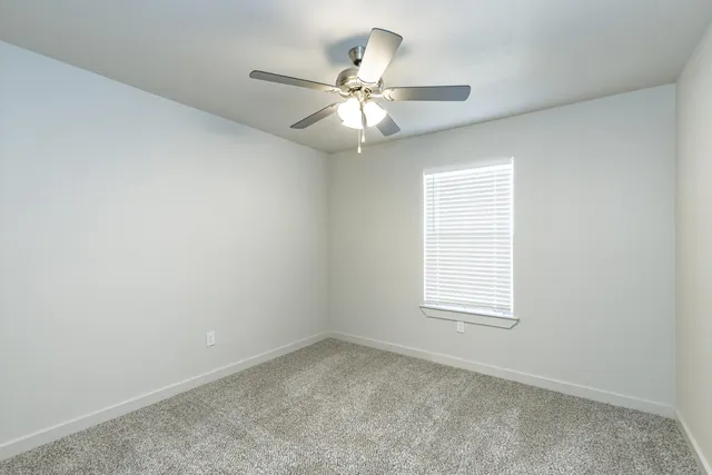 an empty room with a window and a fan