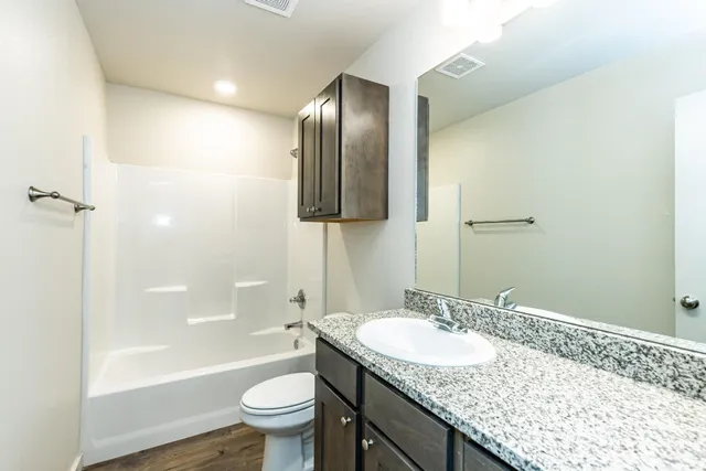 a bathroom with a granite countertop sink toilet and shower