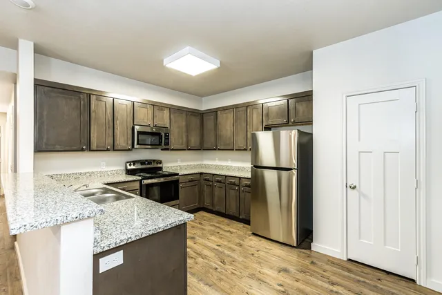 a kitchen with stainless steel appliances granite countertop a refrigerator stove microwave and sink